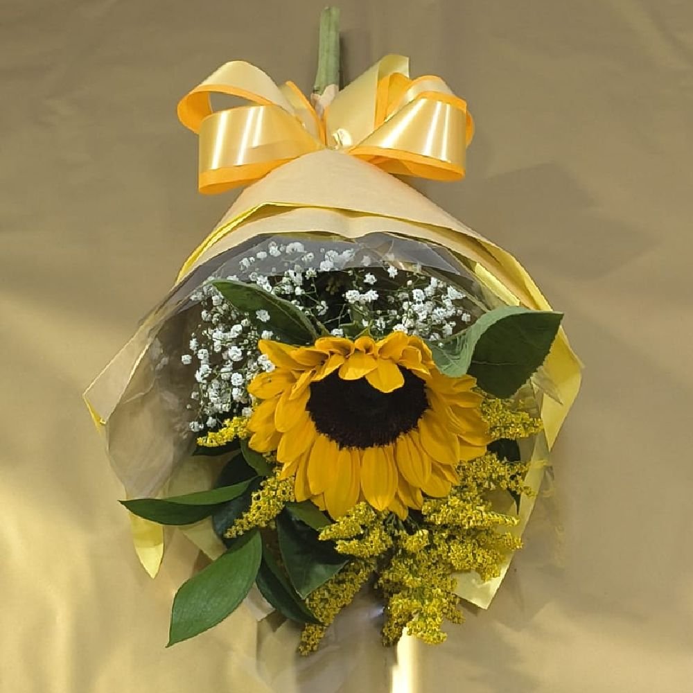 Um girassol decorado com folhagens e laço para presente - Floricultura Curitiba.
